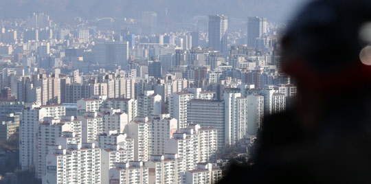 한 시민이 서울 남산에서 강북 아파트 밀집 지역을 바라보고 있다. <연합뉴스>